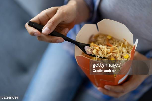 close-up on a happy woman at work eating chinese takeaway for lunch - chinese cuisine stock pictures, royalty-free photos & images