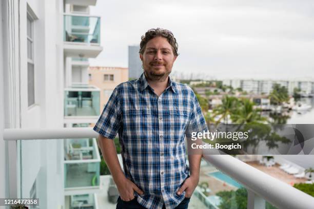 portrait of a caucasian miami man in 30s standing on balcony with a view - mid adult men stock pictures, royalty-free photos & images