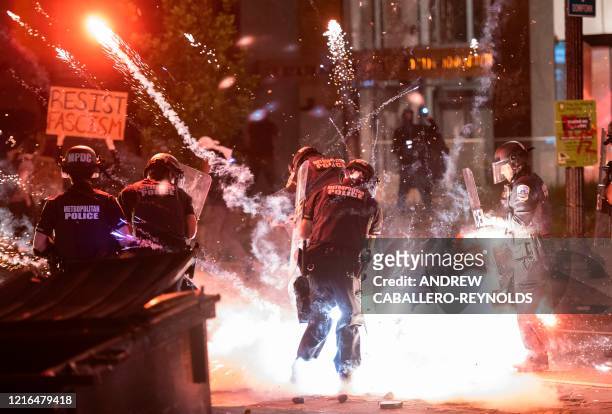 Firecracker thrown by protesters explodes under police one block from the White House on May 30, 2020 in Washington DC, during a protest over the...