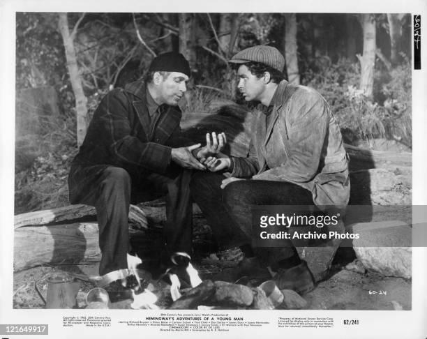 Unidentified actor speaks to Richard Beymer at a campfire in a scene from the film 'Hemingway's Adventures Of A Young Man', 1962.