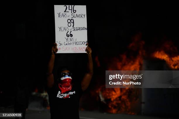 An African-American male poses with a sing in front of burning police vehicles as protestors clash with police near City Hall, in Philadelphia, PA on...