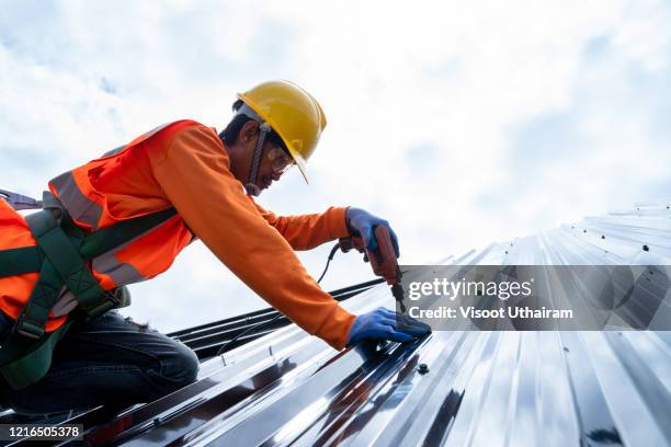 mechanic working screw on the new roofs - sun safety stock pictures, royalty-free photos & images