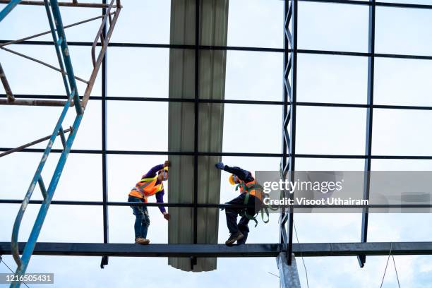 construction worker wearing safety harness belt during working installing new roof. - construction worker office people stock pictures, royalty-free photos & images