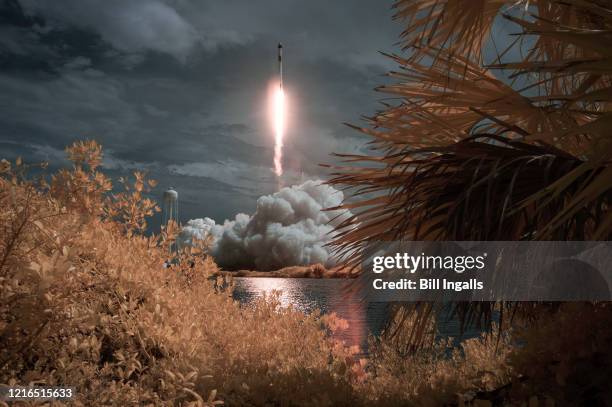 In this NASA handout image, A SpaceX Falcon 9 rocket carrying the company's Crew Dragon spacecraft is seen in this false color infrared exposure as...