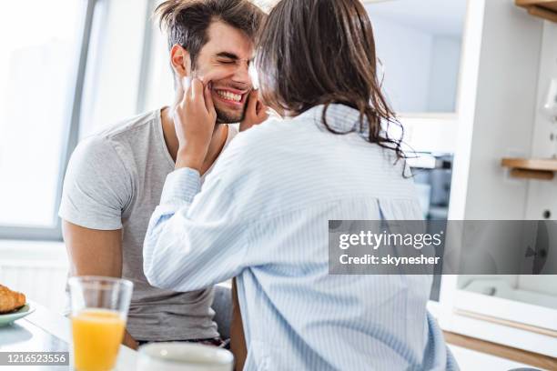 woman having fun while pinching her boyfriend for cheeks in the morning. - cheek stock pictures, royalty-free photos & images