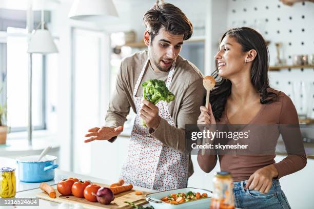 young couple singing while preparing food in the kitchen. - couple singing stock pictures, royalty-free photos & images