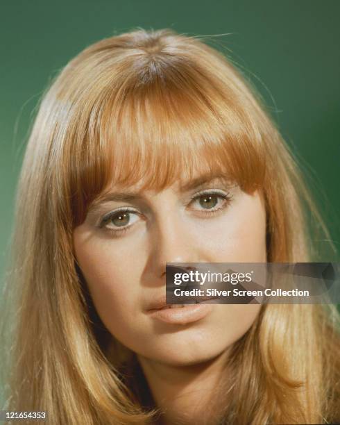 Headshot of Susan George, British actress, in a studio portrait, against a green background, circa 1975.
