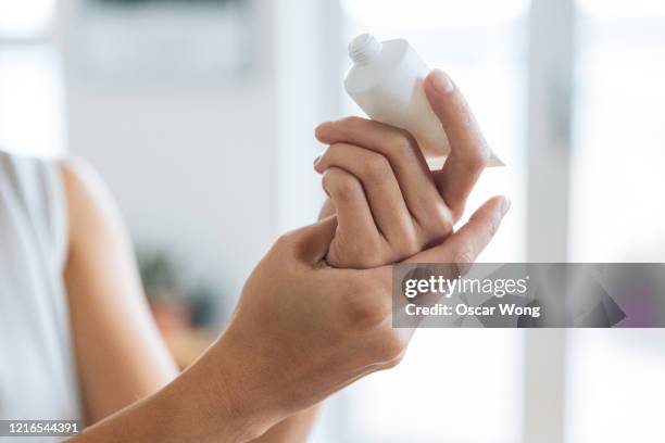 close up shot of young woman rubbing hand sanitiser on hand to prevent spreading of the coronavirus ( covid-19) - mains jointes photos et images de collection