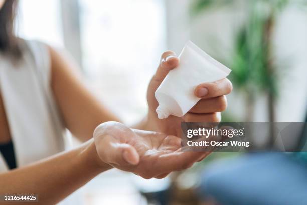 young woman squeezing hand sanitiser on hand to prevent spreading of the coronavirus ( covid-19) - hand cream 個照片及圖片檔