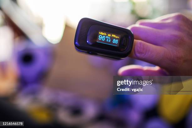 covid-19 oximeter for checking oxygen saturation in blood - pulse oximeter stock pictures, royalty-free photos & images