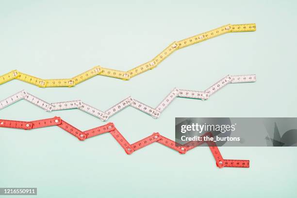 high angle view of folding rulers in shape of a stock curve on turquoise background - ruler stock pictures, royalty-free photos & images