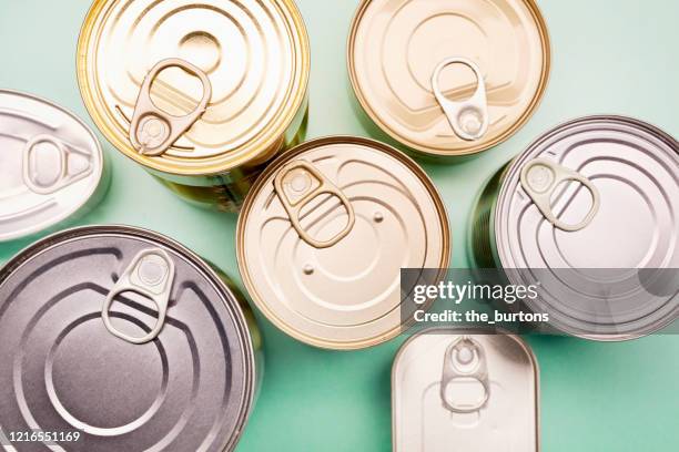 directly above shot of canned food on turquoise background - canned food stock-fotos und bilder