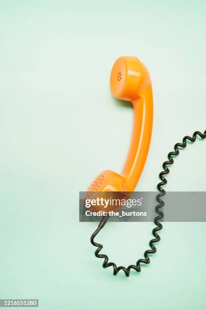 high angle view of an orange old-fashioned telephone receiver on turquoise background - old phone fotografías e imágenes de stock