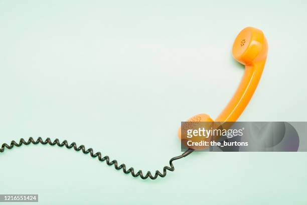 high angle view of an orange old-fashioned telephone receiver on turquoise background - telefonlur bildbanksfoton och bilder