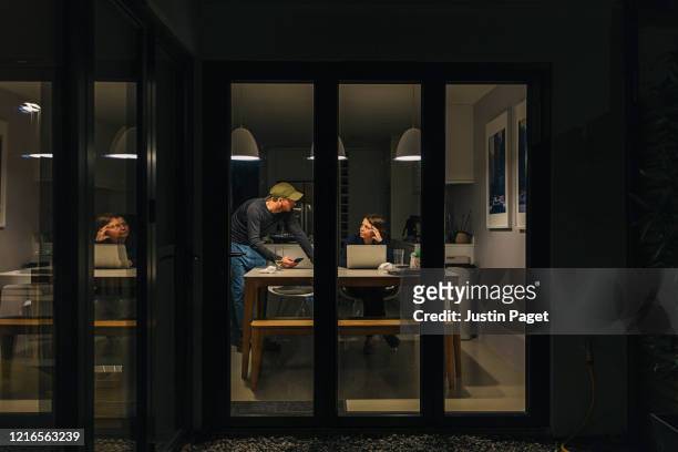 woman working from home late. partner offers support - photographed through window stock pictures, royalty-free photos & images