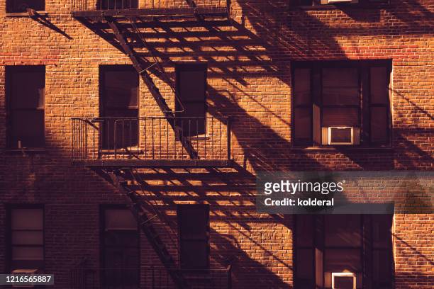fire escapes of residential building in manhattan at midday - brick house stock pictures, royalty-free photos & images
