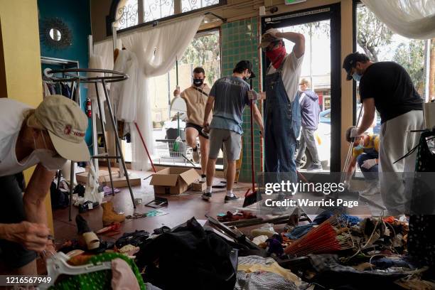 Volunteers and store owners clean up damage done to their stores, after demonstrations followed by unrest protesting the murder of George Floyd, on...