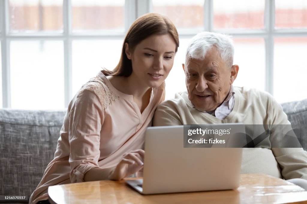 Adult daughter old father choose services via internet using computer