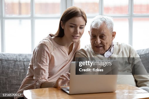 Adult daughter old father choose services via internet using computer Adult daughter old father choose services via internet using computer