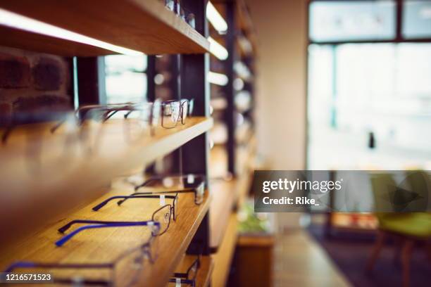 glazen in de winkel van een opticien gesorteerd in een rij op de plank - optician stockfoto's en -beelden