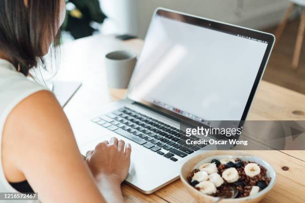 close up shot of a young woman using laptop while having breakfast - breakfast meeting stock pictures, royalty-free photos & images