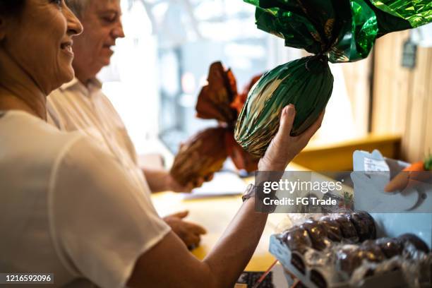 senior couple buying easter egg in a store - convenience chocolate stock pictures, royalty-free photos & images