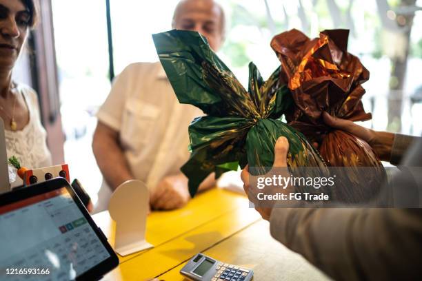 owner selling easter egg for a senior couple in a store - chocolate easter egg stock pictures, royalty-free photos & images