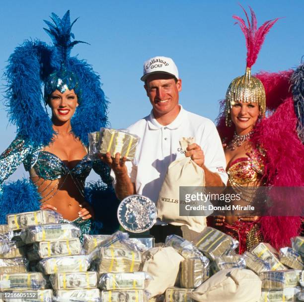 Jim Furyk of the United States celebrates with the trophy and two showgirl performers after winning the PGA Las Vegas Invitational golf tournament on...