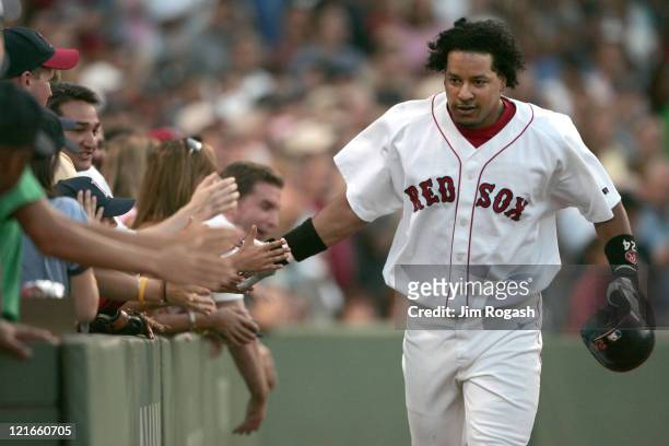Boston Red Sox batter Manny Ramirez touches the hands of fans after he hit the first of two home runs against Texas Rangers, Saturday, July 10, 2004....
