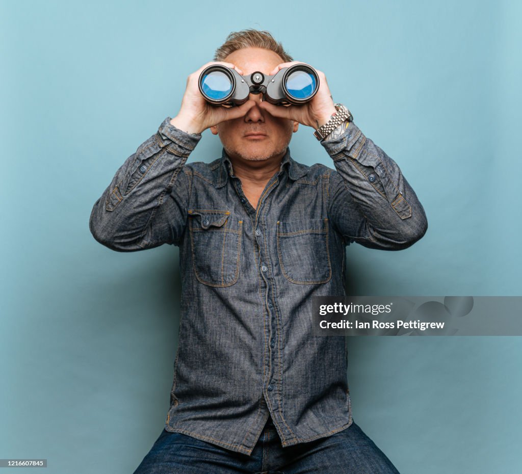 Hipster man with tattoos looking through binoculars