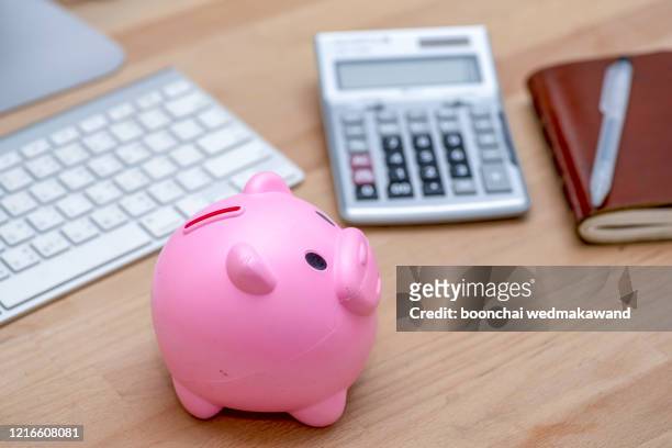 savings and investment concept, pink piggy bank with calculator on pile or economic analysis report chart and graph on office table. - budget ストックフォトと画像