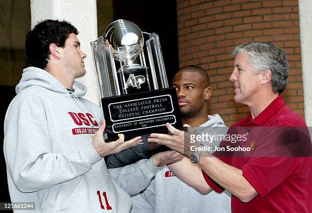 Head coach Pete Carroll of the University of Southern California hands the Associated Press 2003 College Football National Championship trophy to...