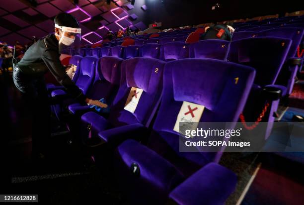 Theater worker cleans seats while wearing a face mask as a preventive measure in a movie theater during the Coronavirus crisis. Thailand is reopening...