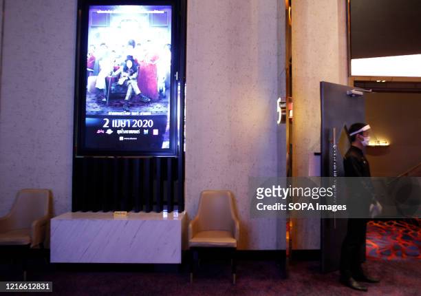 Theater worker stands at a doorway of a movie theater while wearing a face mask as a preventive measure during the Coronavirus crisis. Thailand is...
