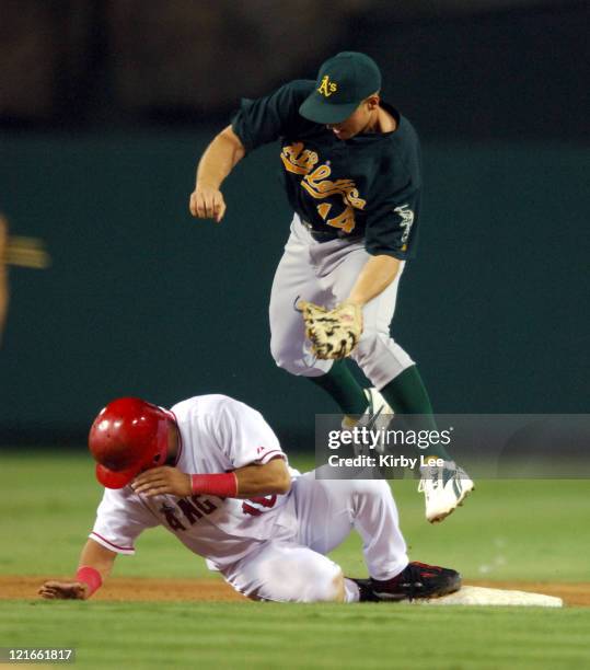 Orlando Cabrera of the Los Angeles Angels of Anaheim slides safely into second base beneath tag of Mark Ellis of the Oakland Athletics on a pick-off...