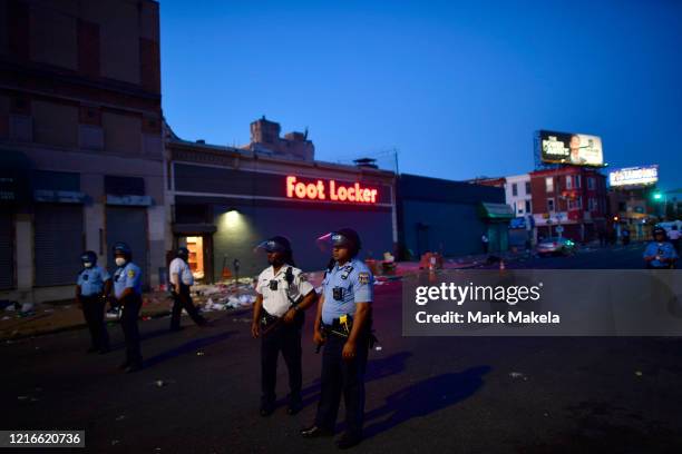 Police monitor activity in front of a Foot Locker store that was looted during widespread unrest following the death of George Floyd on May 31, 2020...