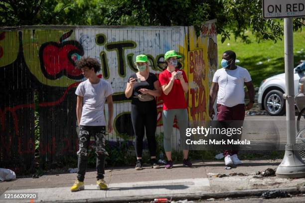People wearing masks observe a large police presence during widespread unrest following the death of George Floyd on May 31, 2020 in Philadelphia,...