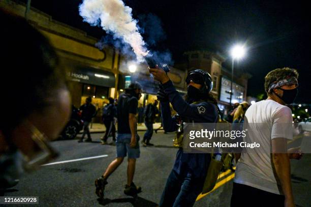 Man fires a concussion grenade back at police officers after the officers threw tear gas during the fourth consecutive day of protests on May 31,...