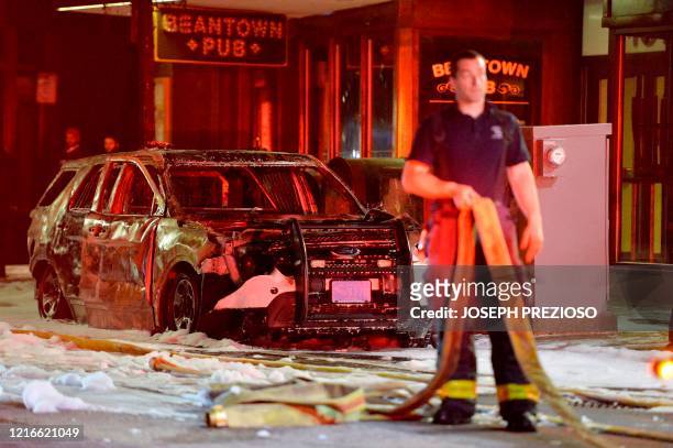 Firefighter stands near a police cruiser that was set on fire after clashes with protesters after a demonstration over the death of George Floyd, an...