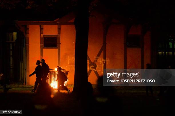 Protesters walk past a small fire during clashes with police after a demonstration over the death of George Floyd, an unarmed black man who died in...