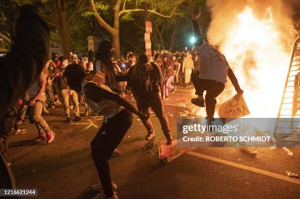 Protesters jump on a street sign near a burning barricade during a demonstration against the death of George Floyd near the White House on May 31,...