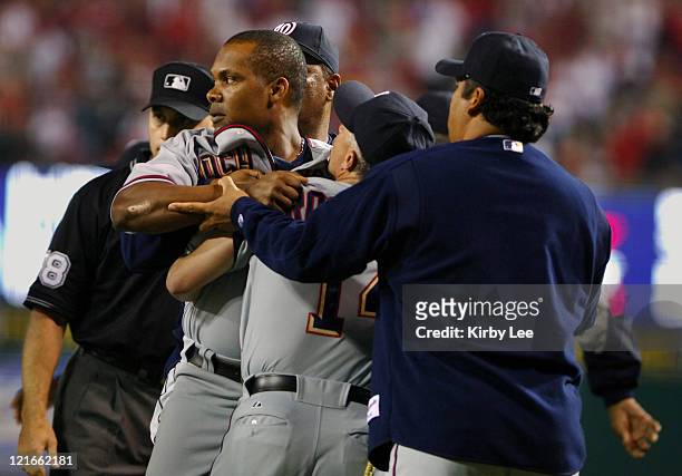 Jose Guillen of the Washington Nationals is restrained by bench coach Eddie Rodriguez and Vinny Castilla after an argument with Los Angeles Angels of...
