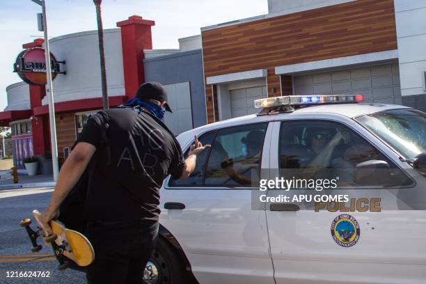 Protestor holds up his middle finger towards the police while they back up as the crowd advances in their direction in downtown Long Beach on May 31,...