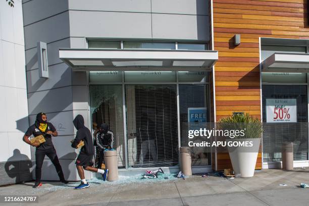 Looters run from a jewelry store in downtown Long Beach on May 31, 2020 during a protest against the death of George Floyd, an unarmed black man who...