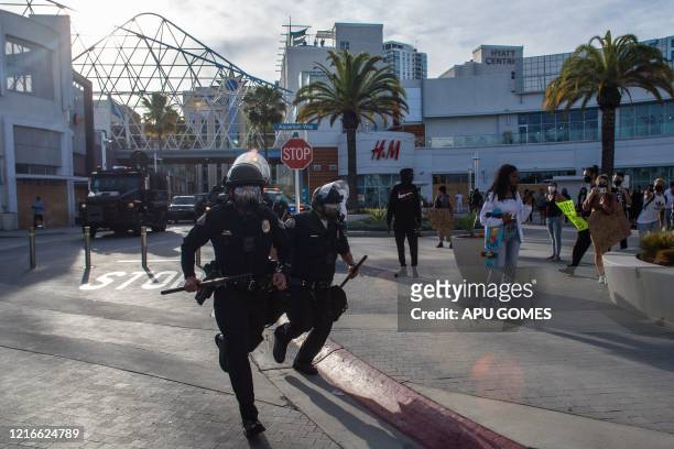 Police officers run in downtown Long Beach on May 31, 2020 during a protest against the death of George Floyd, an unarmed black man who died while...