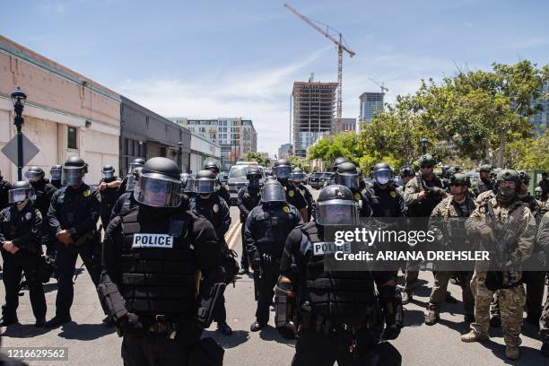 San Diego Police officers in riot gear and a special tactics group face-off with demonstrators in downtown San Diego, California on May 31 as people...