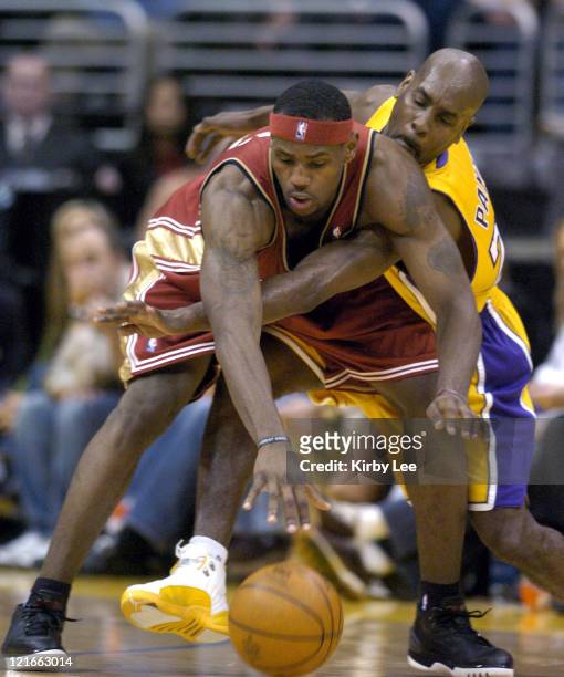 LeBron James of the Cleveland Cavaliers battles Gary Payton of the Los Angeles Lakers for the ball during the game between the Cleveland Cavaliers...