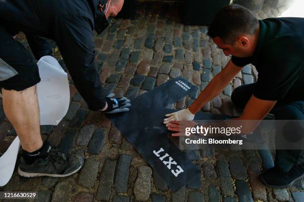 Workers stick a direction arrow to the cobbles on the floor at Camden Market ahead of its re-opening in London, U.K., on Monday, June 1, 2020....