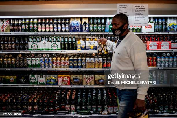 Man takes beers from a fridge inside a liquor shop at the Bara taxi rank in Soweto, Johannesburg, on June 1, 2020. - South Africa moved into level...