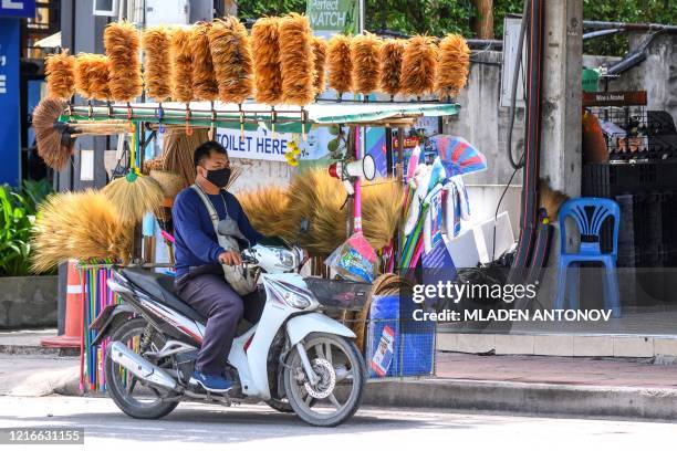 Vendor sells brooms and dusters from his motorbike in Pattaya on June 1, 2020. Authorities lifted coronavirus restrictions for all the beaches in...